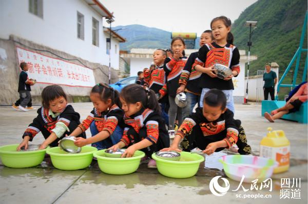 美姑县洛俄依甘乡新农村幼教点的孩子们饭后自己洗碗。人民网 朱虹 摄